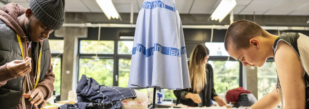 Two students creating new clothes from recycled materials.
